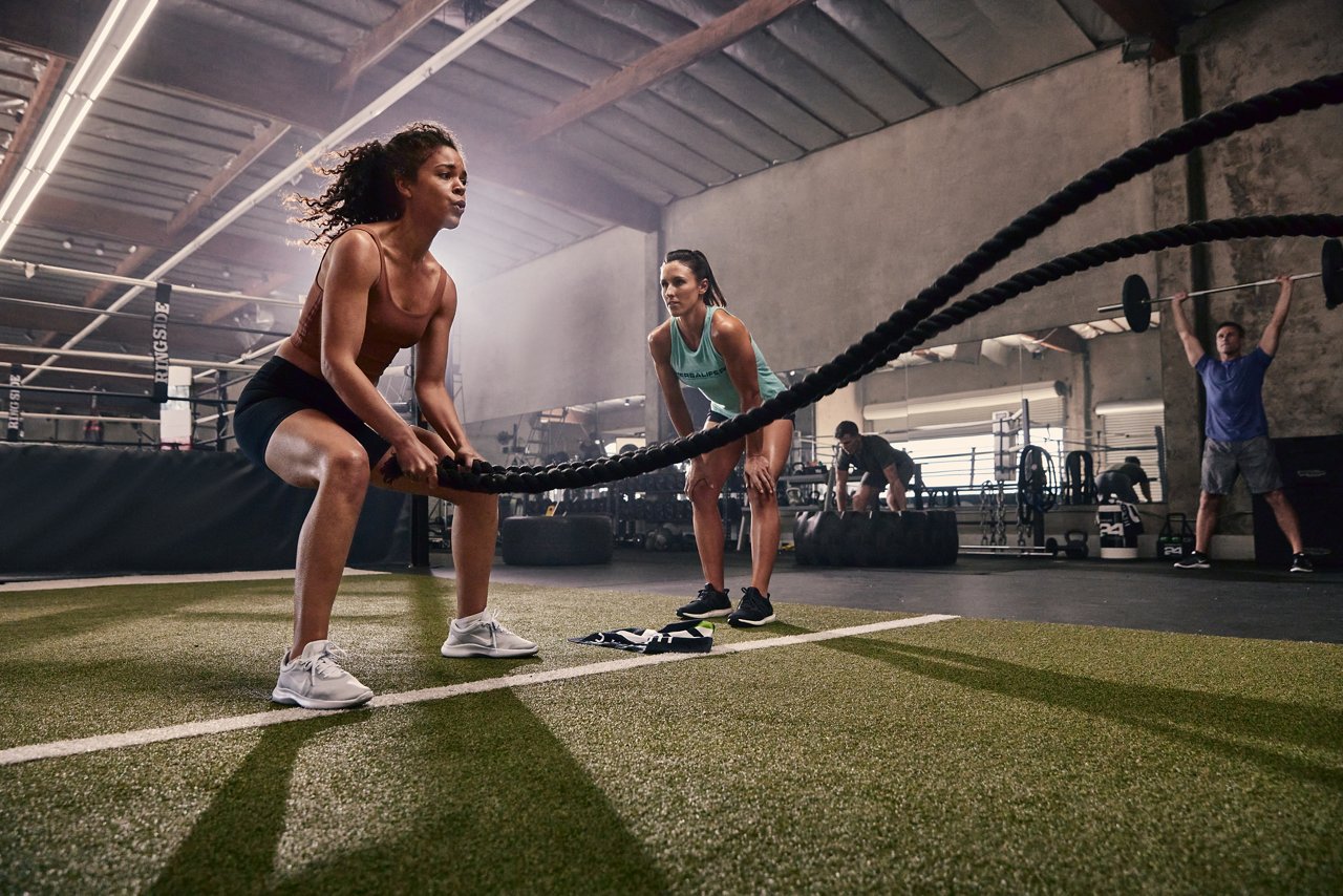 Athletic woman doing battle ropes at the gym