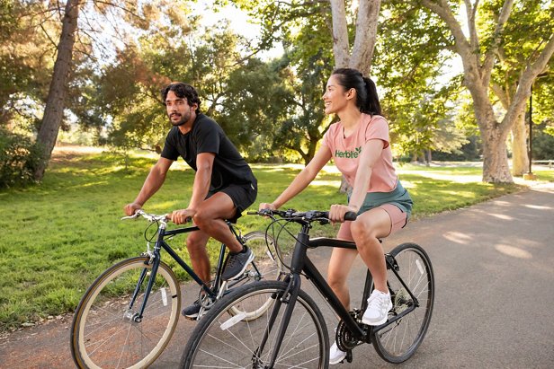 Man and woman riding their bicycles in a park.