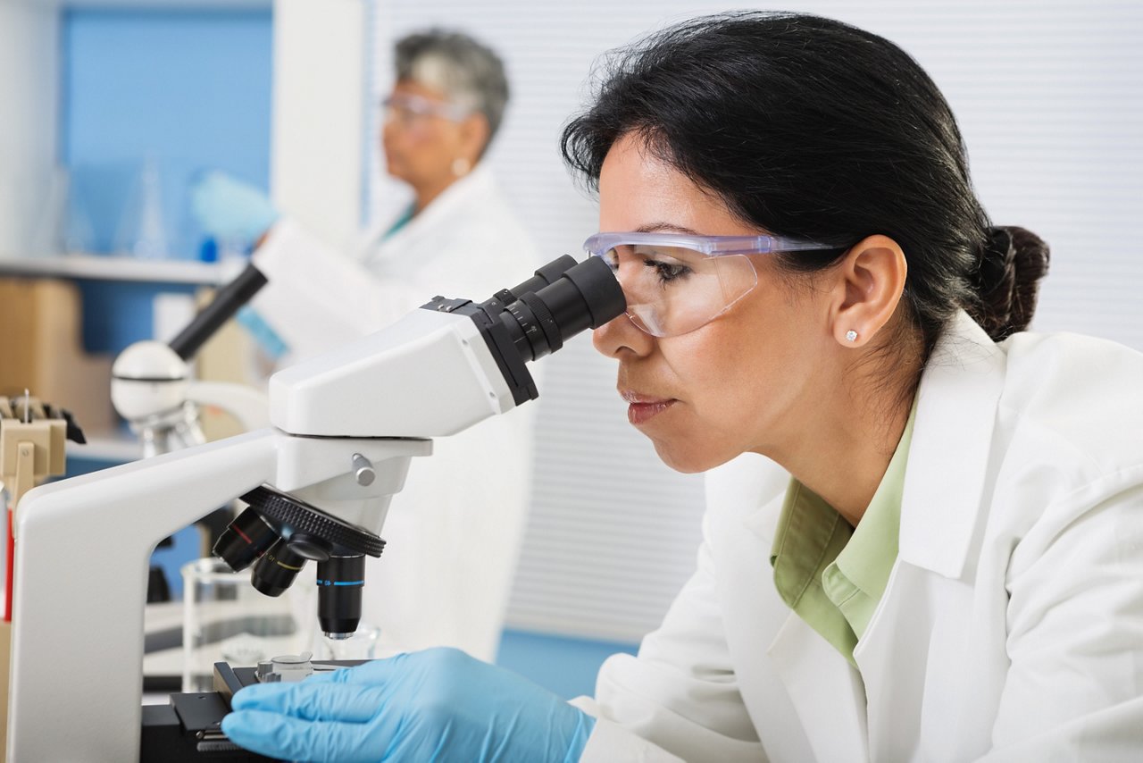 A scientist looking through a microscope A scientist looking through a microscope
