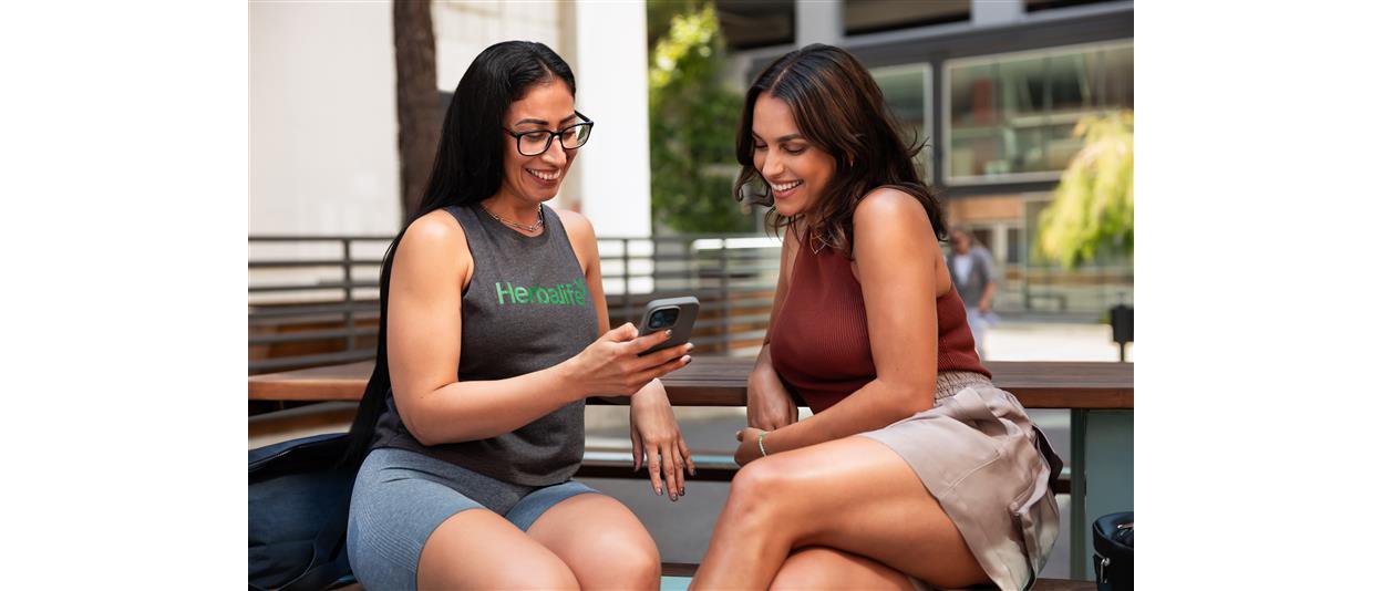 Two women smiling while looking at a cell phone